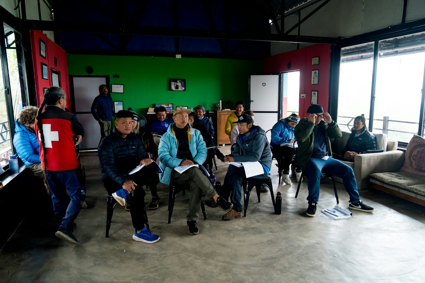Persone sedute su sedie che tengono documenti durante un workshop al chiuso.